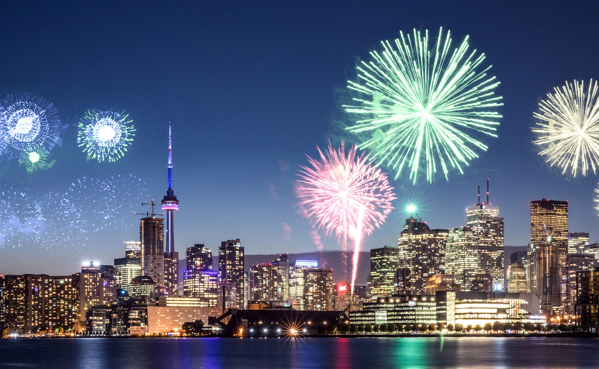 night scene of CN Tower and downtown Toronto skyline with fireworks exploding overhead